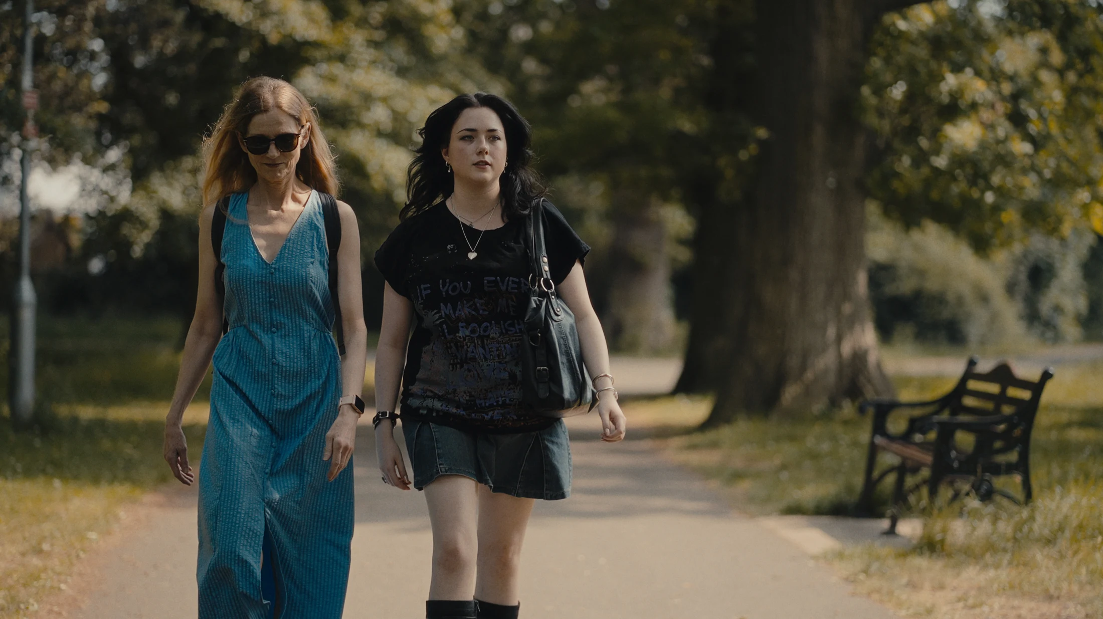 Two women walking together through a sunlit park, from the film.